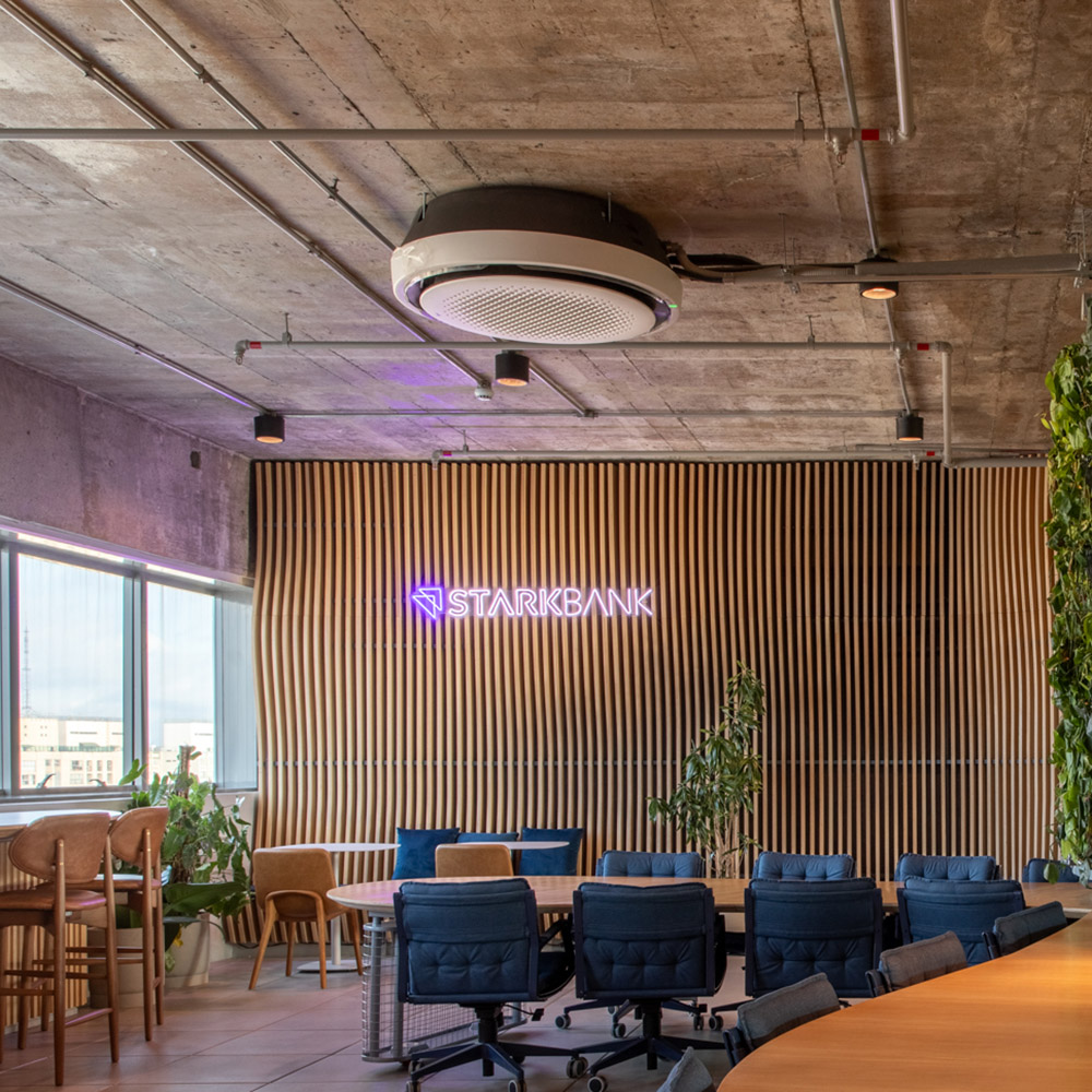 Sala de reunião com o logotipo do Stark Bank em neon sobre a parede de ripas