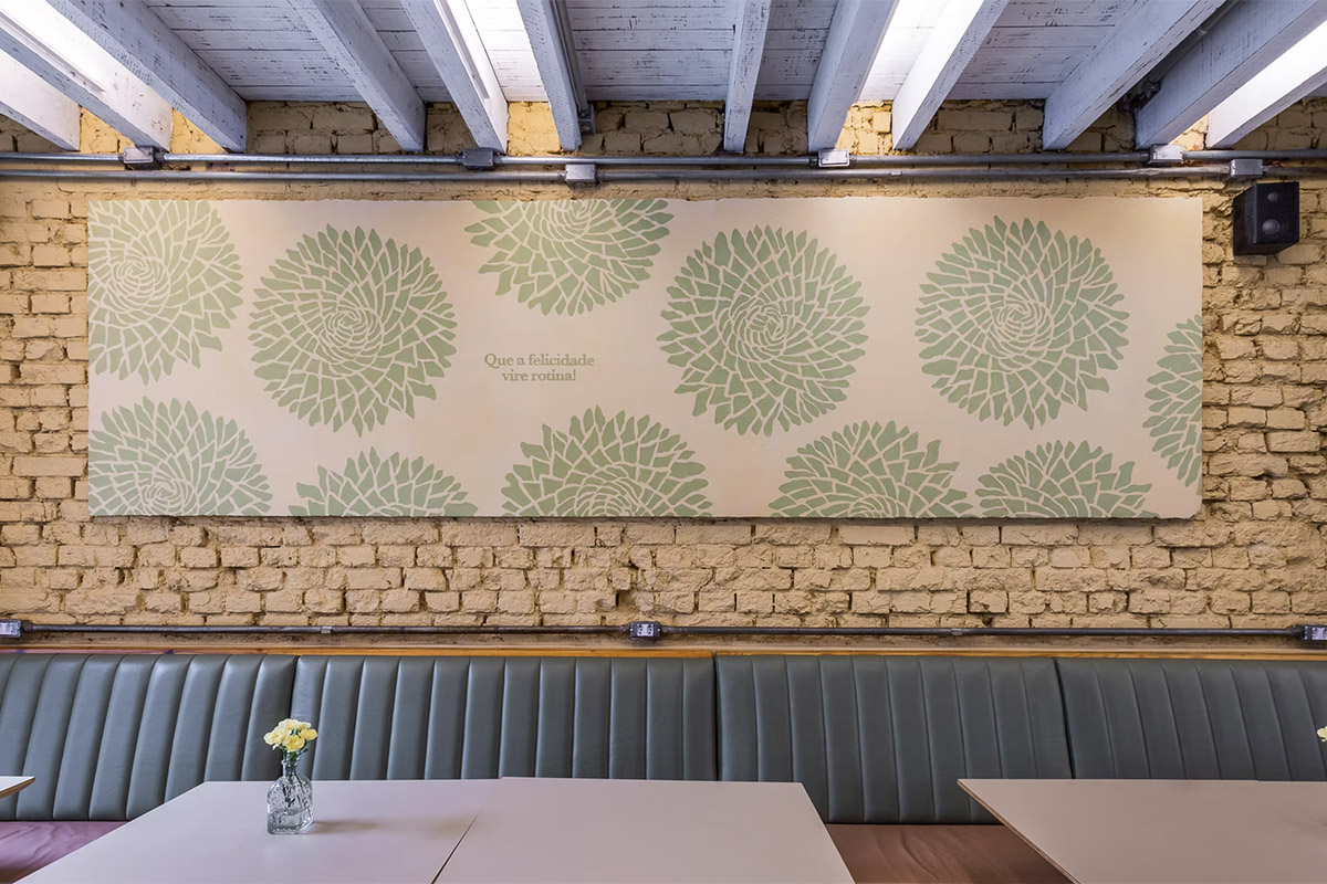 Painel com padrão floral verde em parede de tijolos, em uma loja Dona Vitamina